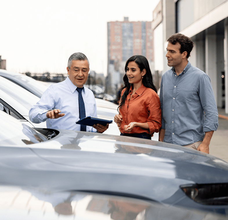Couple exploring car options with salesman.