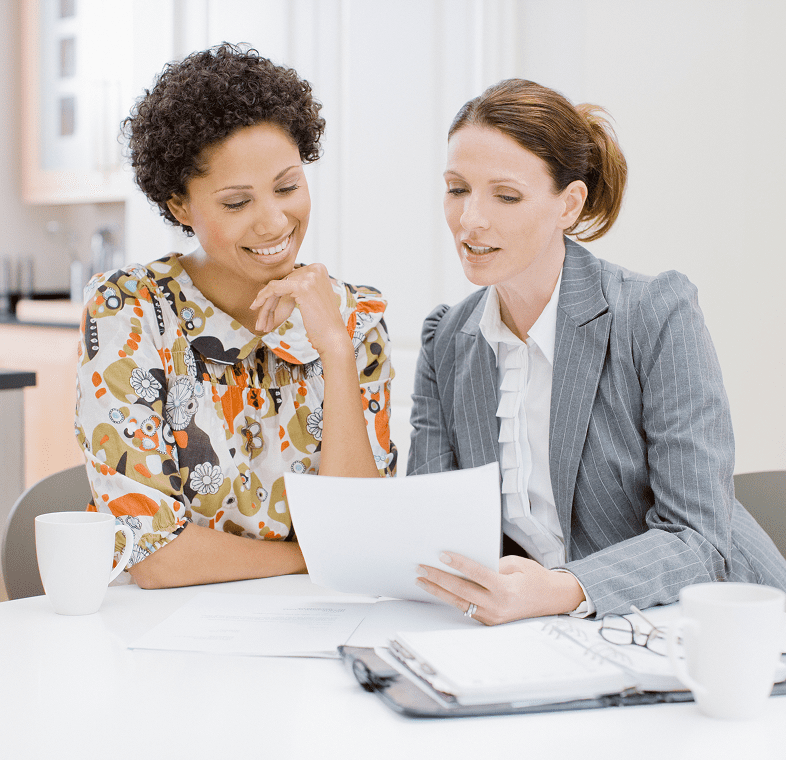 Two women discussing documents at table
